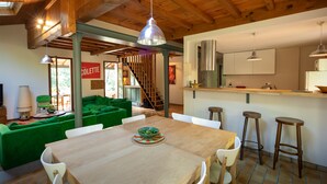 Una cocina moderna con una isla de madera, taburetes de bar y una mesa de comedor con sillas.
