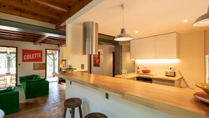 Una cocina moderna con encimeras de madera, una lámpara colgante y un lavavajillas visible.