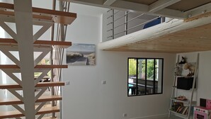 Un'ampia zona giorno con una scala in legno, una grande finestra vista su spazi verdi e una libreria con giochi per bambini.