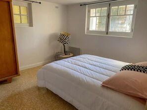 A bedroom with a bed, a nightstand, a lamp, and a window.