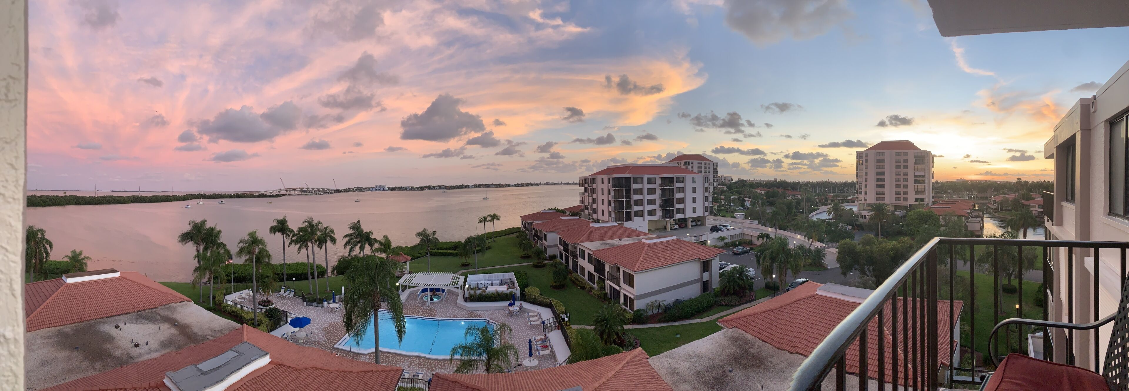 Un hôtel doté d’une piscine, offrant une vue sur l’eau et un magnifique coucher de soleil.