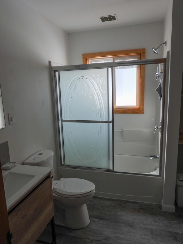 A modern bathroom with a glass-enclosed shower, a toilet, and a sink. - Ideal getaway for nature lovers! (East Tawas)