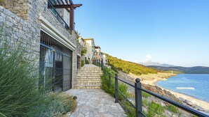 A stone pathway leading to a beach with a view of the sea and mountains. - Lustica Bay Central (Radovici)