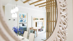 A modern living room with a wooden ceiling, a TV mounted on the wall, and a dining area with a table and chairs. - Lustica Bay Central (Radovici)