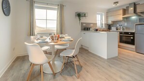 A modern kitchen with white cabinetry, a central island, and a dining area with white chairs and a round table.