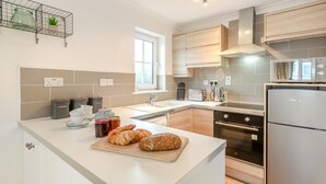 A modern kitchen with a central island, stainless steel appliances, and a window providing natural light.
