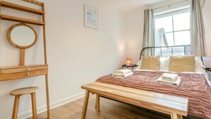 A bedroom with a wooden bed, bedside table, and a small stool.