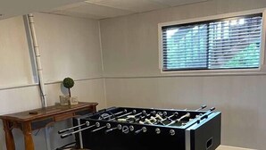 A foosball table in a room with a window and a desk.