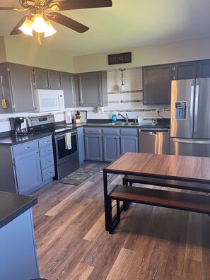 A modern kitchen with grey cabinets, a stainless steel refrigerator, a microwave, and a coffee maker. - Beautiful home in quiet neighborhood (Sturgis)