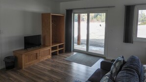 A living room with a wooden entertainment unit, a sofa, and a sliding glass door leading to an outdoor area.