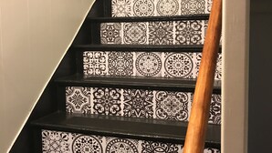 Una escalera con baldosas blancas y negras en diseño geométrico y barandilla de madera.