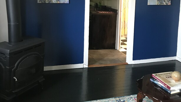 Una habitación con un estufa de leña de madera oscura, una pared de acento azul y dos cuadros con motivos de ciervo.