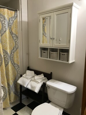 Een badkamer met toilet, een kast met planken en een decoratieve douchegordijn.
