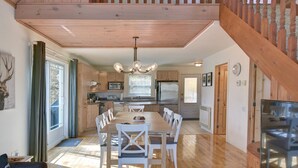 Une cuisine spacieuse avec des meubles en bois, une table à manger avec des chaises et un lustre.