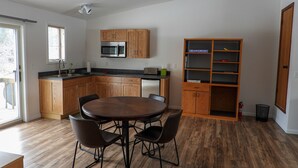 Una cocina moderna con armarios de madera, un microondas integrado y un comedor con una mesa redonda y sillas.