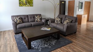 Una sala moderna con un sofá seccional gris, una mesa de centro de madera oscura y una alfombra estampada.