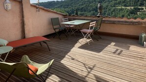 A wooden deck with a table and chairs, a white canopy, and a view of a forested hill. - Village house in Provence with lovely 2-bedroom roof terrace (Niozelles)