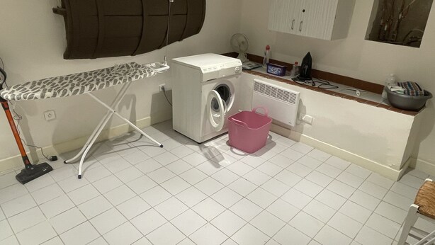 A laundry area with a washing machine, an ironing board, a bucket, and a large barrel. - Village house in Provence with lovely 2-bedroom roof terrace (Niozelles)