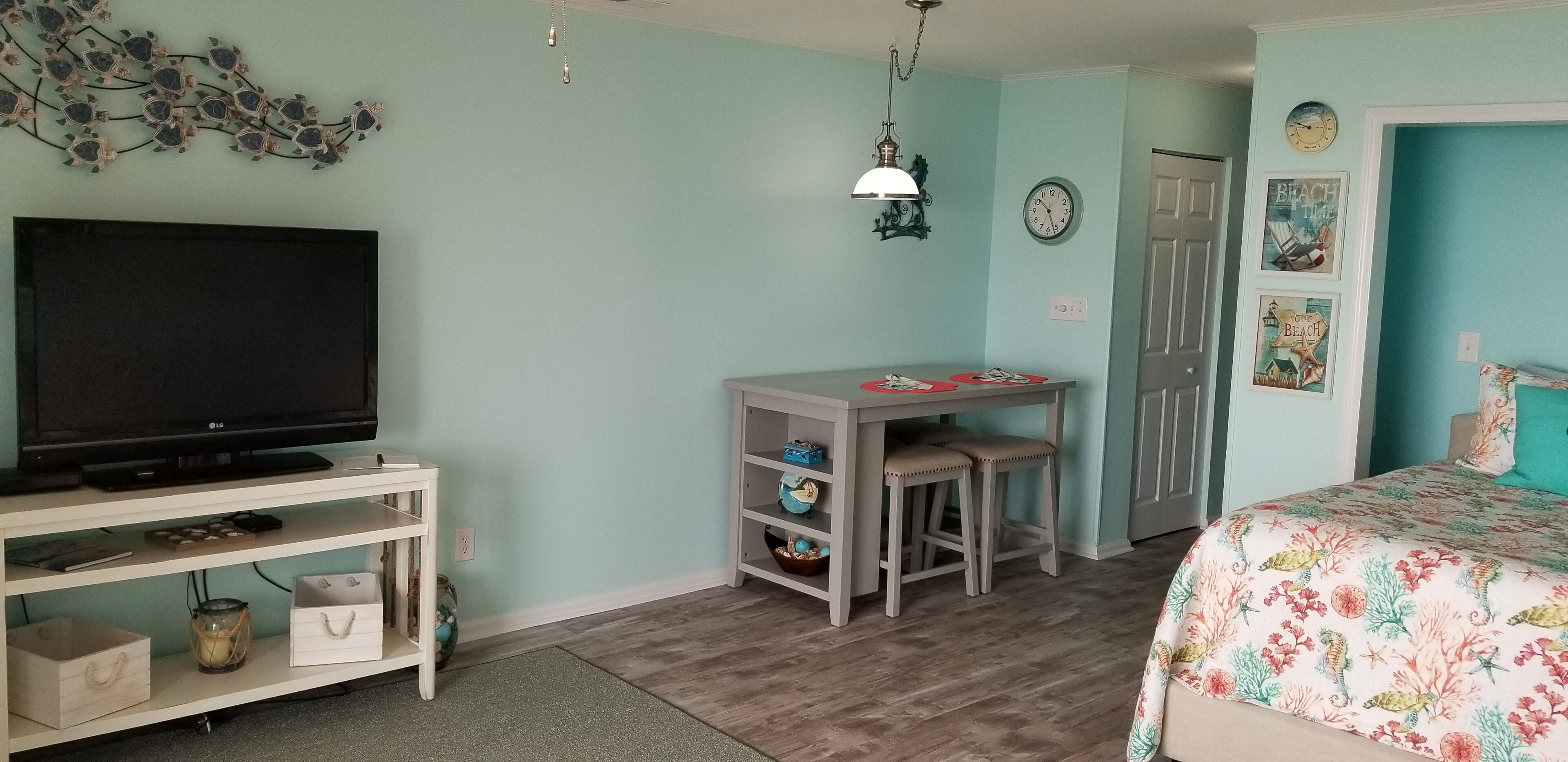 Un dormitorio con cama, televisor, escritorio y silla.