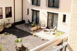 A courtyard with outdoor seating, potted plants, and a building with balconies.