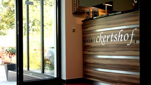 A reception desk with a wooden panel design and the name 'Bruckertshof' in cursive. - Bruckertshof Hotel (Bamberg)
