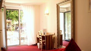 A hotel room with a bed, a desk, and a chair. There is a large mirror on the wall and a sliding glass door leading to an outdoor area. - Bruckertshof Hotel (Bamberg)