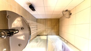 A shower with a handheld showerhead, a wall-mounted fan, and a tiled floor. - Bruckertshof Hotel (Bamberg)
