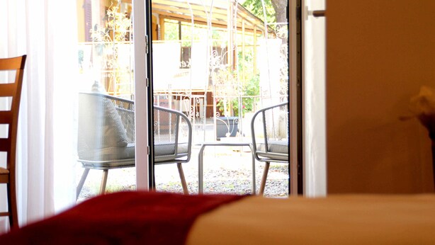 A room with a bed, a window with a view of an outdoor patio area with chairs and a table. - Bruckertshof Hotel (Bamberg)