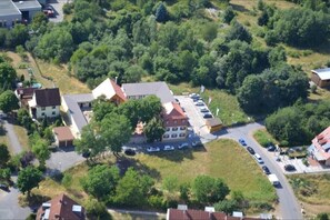 An aerial view of a residential area with houses, a parking lot, and surrounding greenery.
