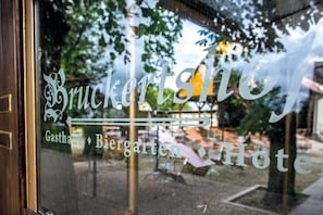 Une fenêtre sur laquelle on peut lire les mots « Bruckertshofen » et « Gasthof Biergarten Hotel », indiquant le nom de l’établissement.