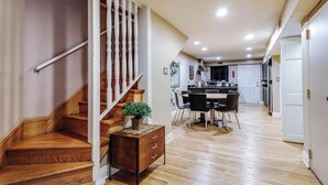 A modern kitchen with a central island, wooden staircase, and a dining area with chairs and a table. - Old-World, Classic Building Downtown (Chicago)