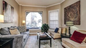 A living room with a sofa, armchair, coffee table, and a large window with blinds. - Old-World, Classic Building Downtown (Chicago)