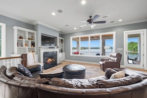 A living room with a fireplace, leather sofa, and a view of the outdoors.