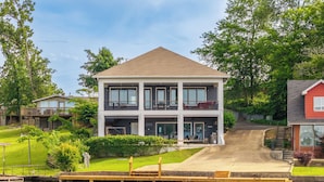 A two-story house with a dock extending into a body of water. - COZY, LUXURY LAKE HOUSE W/ STUNNING LAKE VIEWS!! (Lake Hamilton)