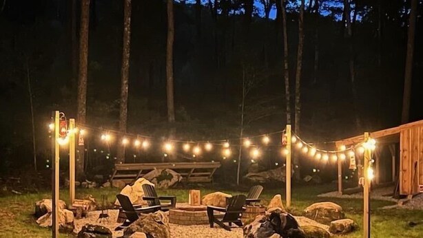Un espacio de estar al aire libre con un brasero, rodeado de rocas y cubierto con un toldo.