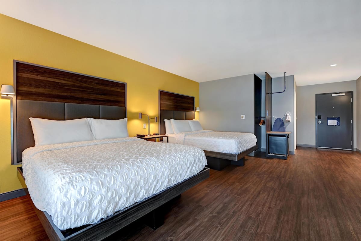 Une chambre d’hôtel avec deux lits, des têtes de lit en bois et un design moderne.