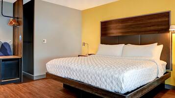 A modern hotel room with a large bed, wooden headboard, and a small bedside table.