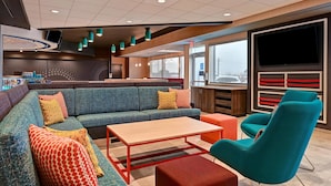 Un espace de détente moderne comprenant un canapé d’angle, une table basse et un fauteuil turquoise.