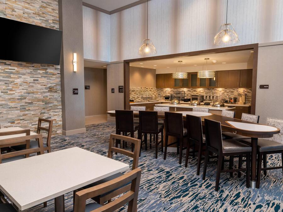 A hotel dining area with a stone wall, a flat-screen TV, and a breakfast bar.