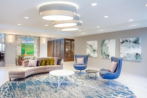 A modern living room with a sectional sofa, two armchairs, a coffee table, and abstract wall art. - Homewood Suites by Hilton Livermore, CA (Livermore)