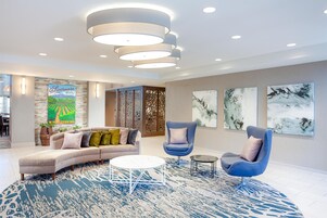 Uma sala de estar moderna com um sofá seccional, duas poltronas, uma mesa de centro e arte abstrata na parede.