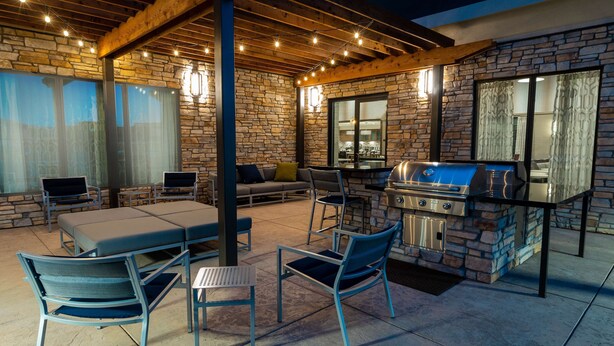 Un patio al aire libre con paredes de piedra, una parrilla y asientos.