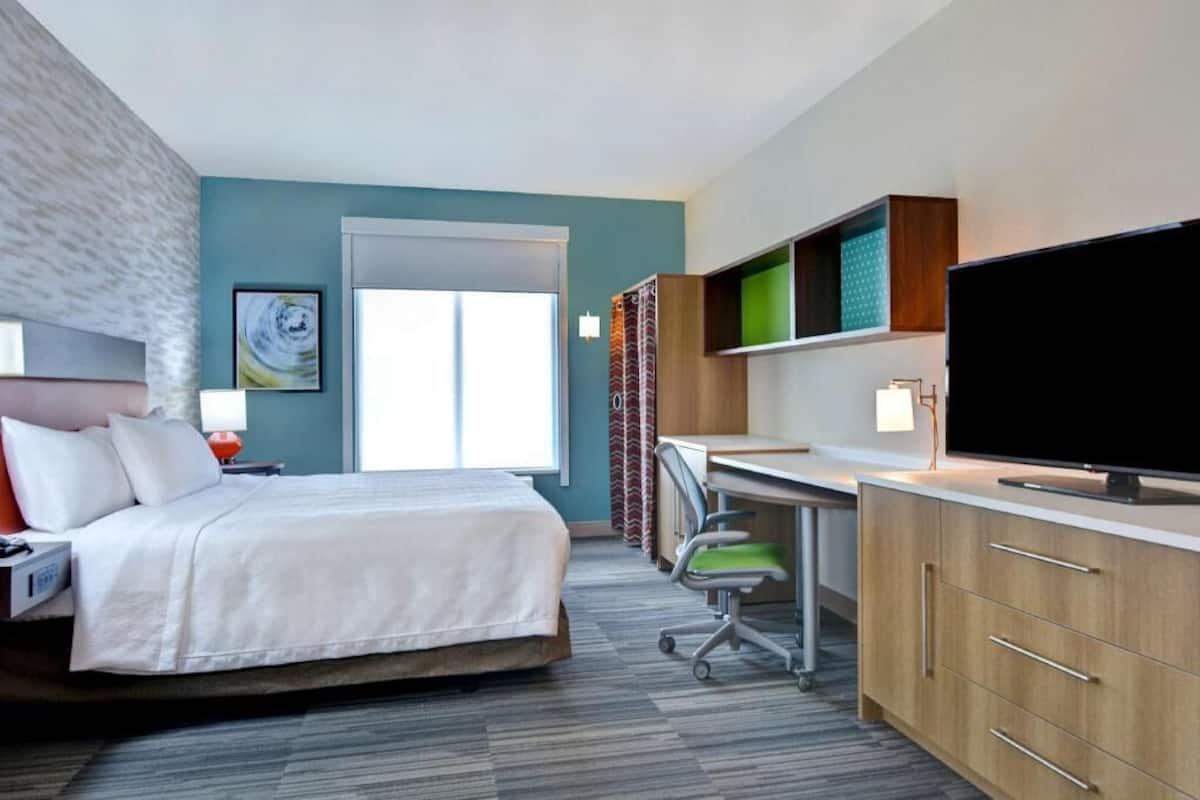 Une chambre d’hôtel avec un lit, un bureau, une télévision et une fenêtre.