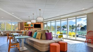 Un intérieur moderne avec un grand canapé, des poufs orange et un téléviseur.