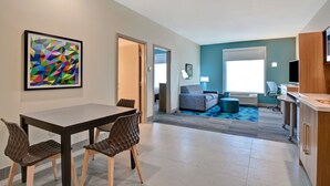 Une chambre d’hôtel moderne dotée d’un coin repas, d’un canapé et d’une télévision.