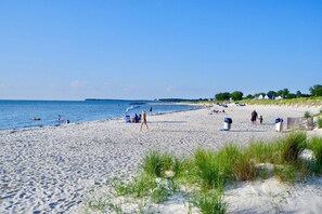 A beach with people, a clear sky, and houses in the background. - Cape Charles - Coastal Elegance, Small Town Charm (Cape Charles)