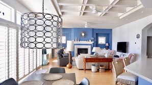 Una sala de estar moderna con chimenea, un comedor con mesa y sillas de madera, y una cocina con televisión y mesa de comedor.