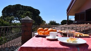 Une table dressée avec de la nourriture et des boissons, un pilier de pierre et une vue sur un bâtiment et des arbres.