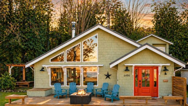 Una casa con terraza, mobiliario exterior y un hogar para la chimenea.