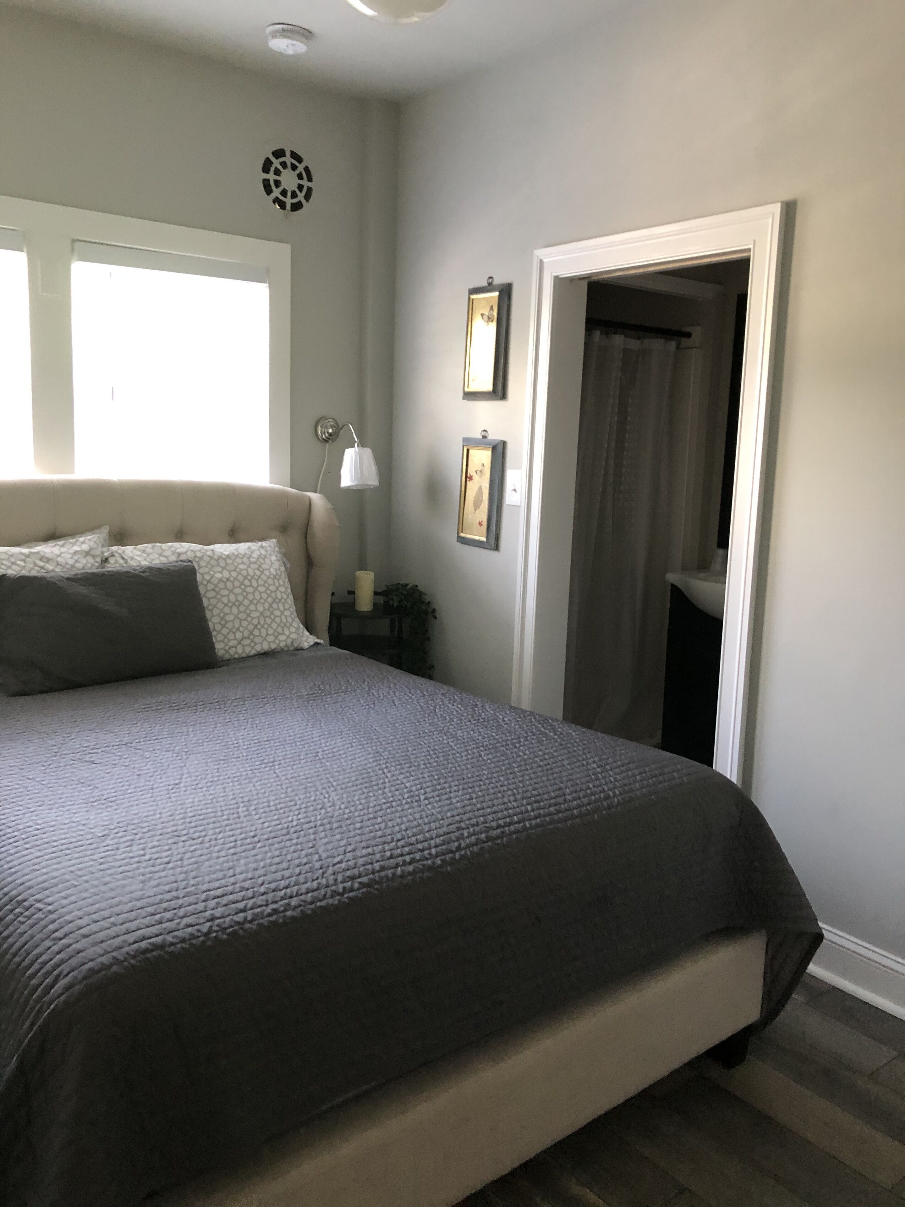 A bedroom with a large bed, a bedside lamp, and a window.